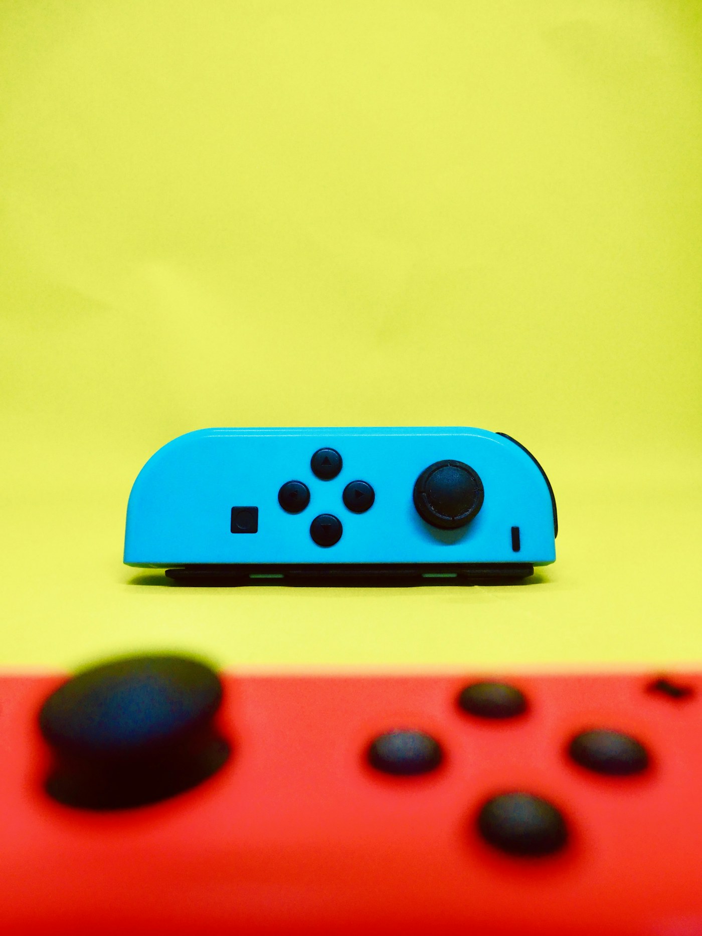 Blue and red Nintendo Switch Joy-Con controllers photographed in a colourful studio setting